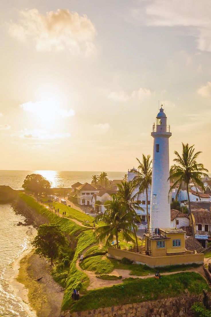 Galle Fort lighthouse at sunset with palms and ocean