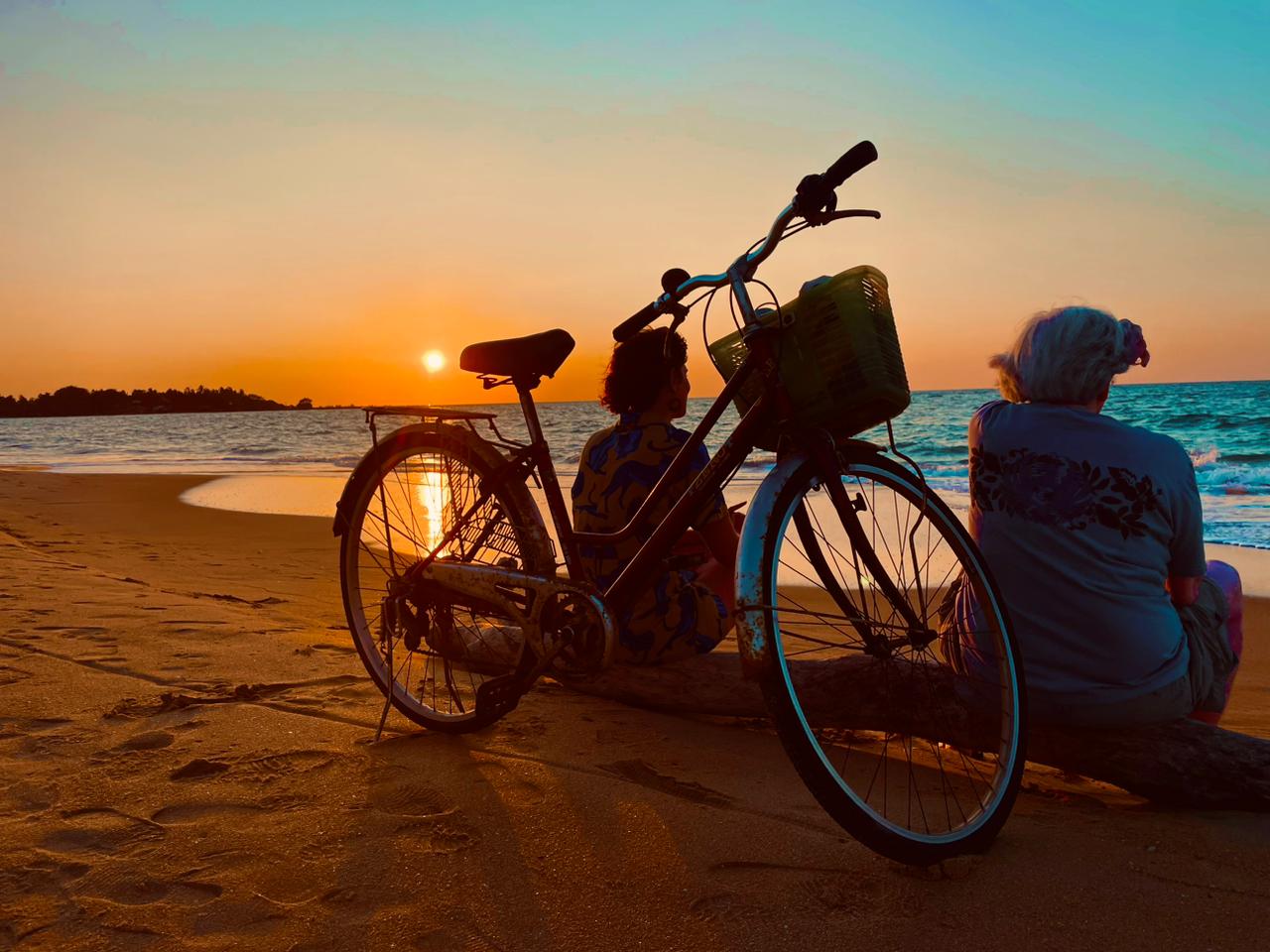 Couple watching the sunset on a southern beach with a bicycle