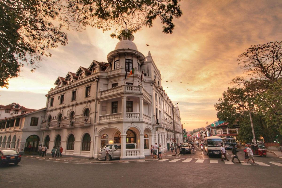 Historic Queen's Hotel in Kandy at dusk with birds and city traffic